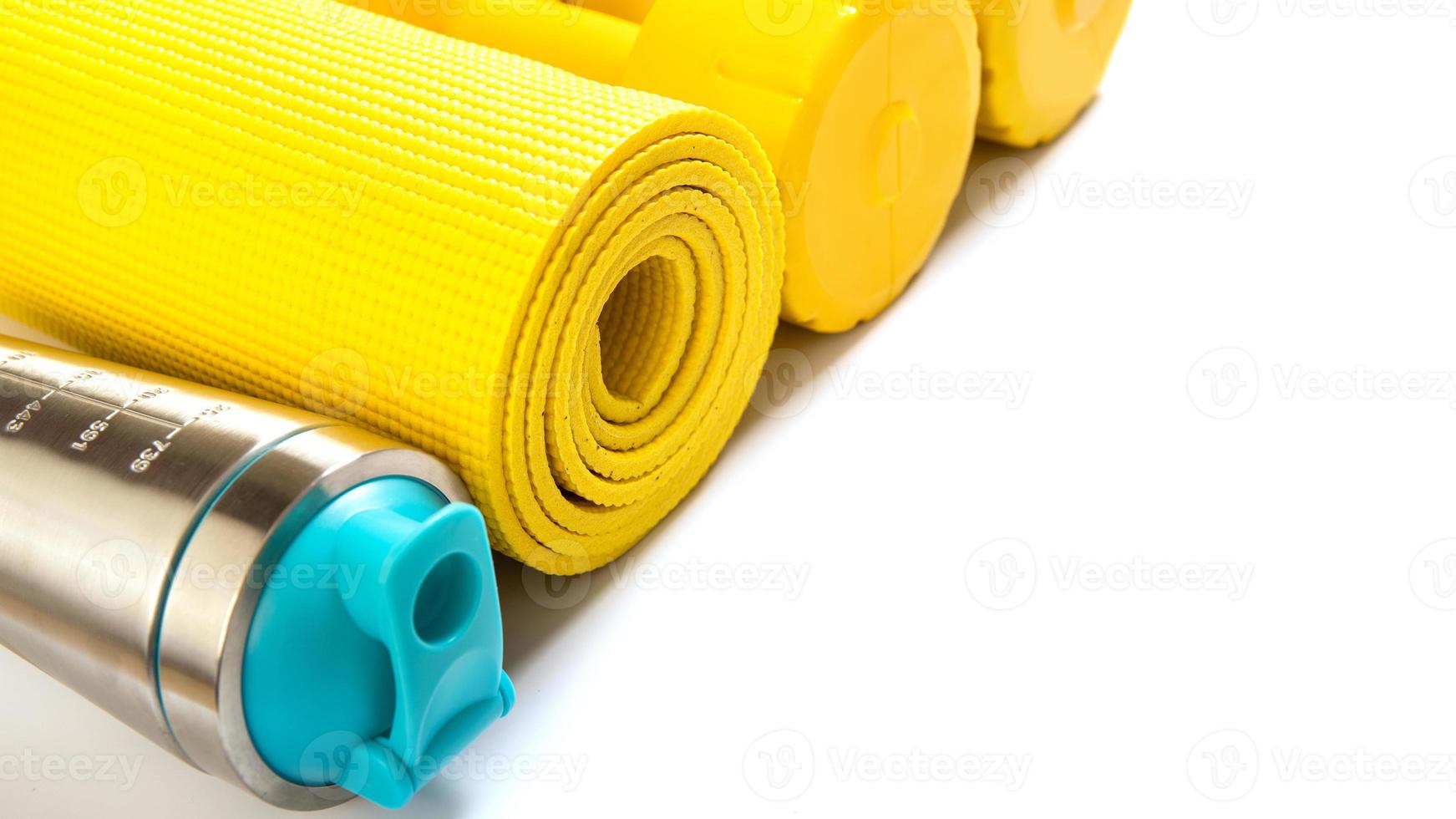 Yellow fitness mat and dumbbells on white background photo