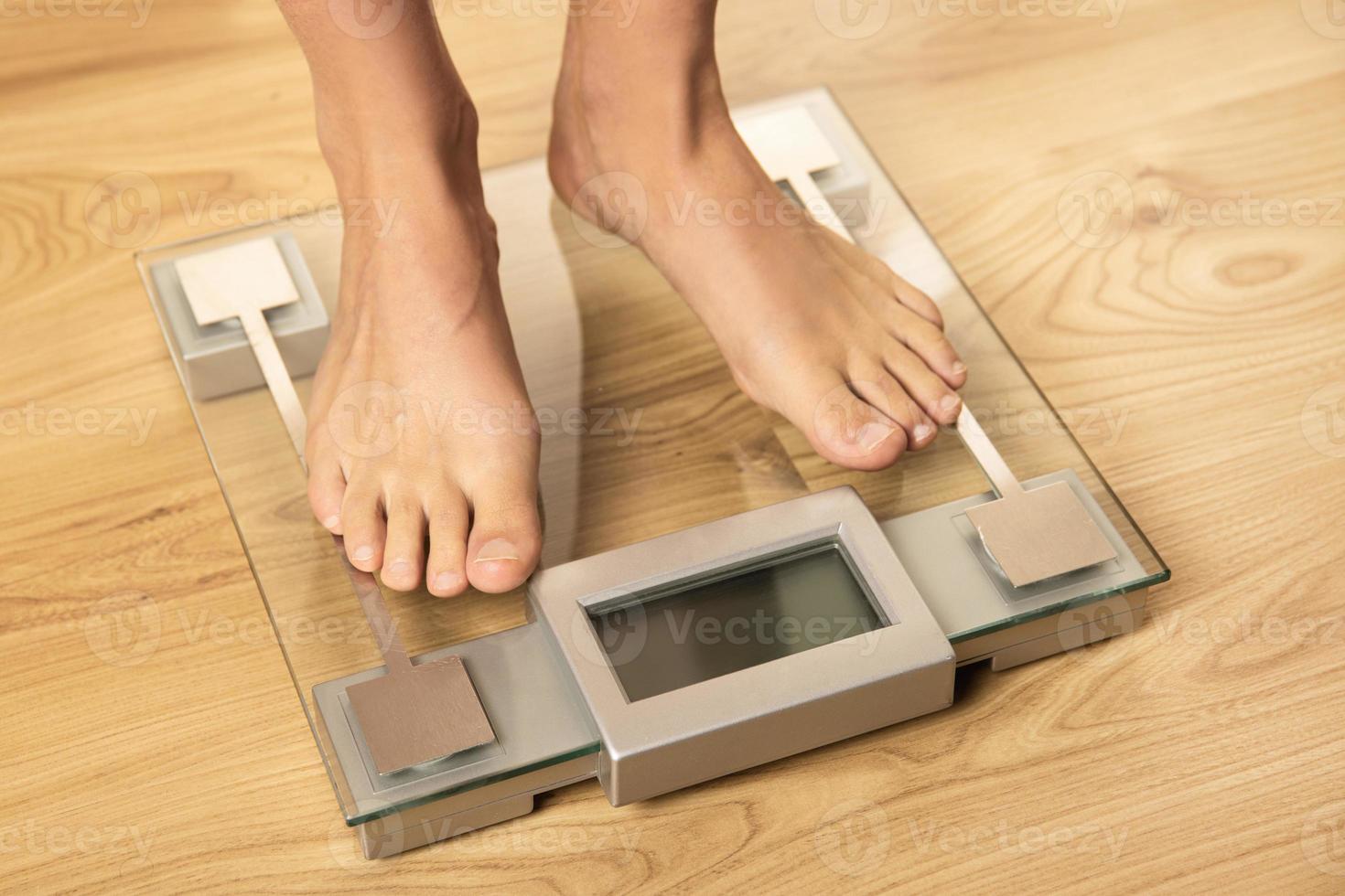 Female feet on the modern digital weighing scale photo