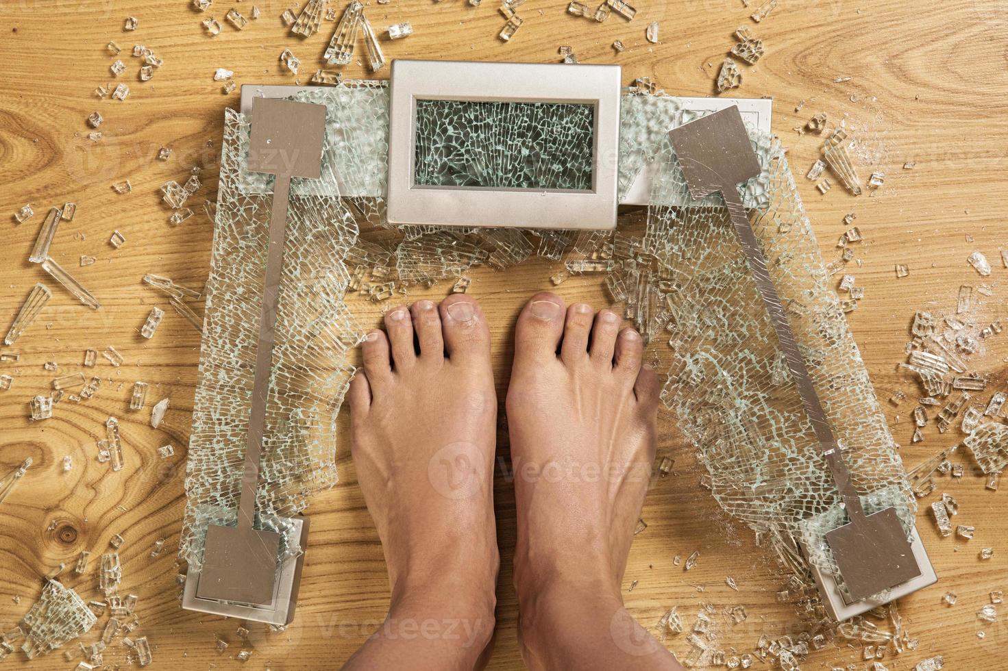 Overweight concept. Female feet and cracked glass weighing scale. photo