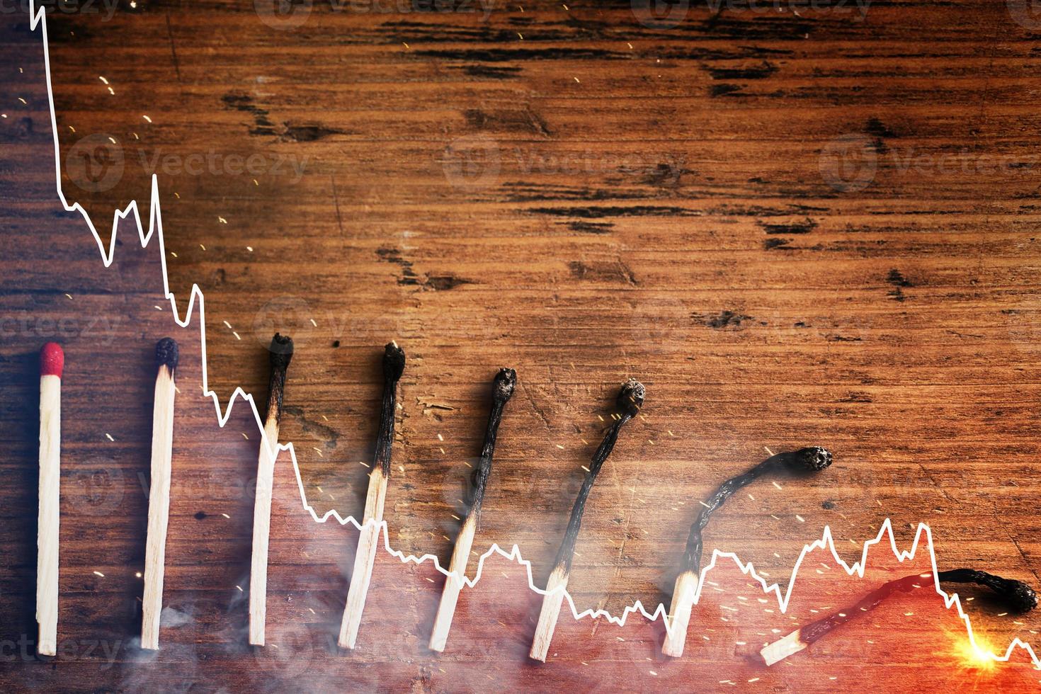 Undamaged and several progressively more burnt out match sticks and falling sparkline chart photo