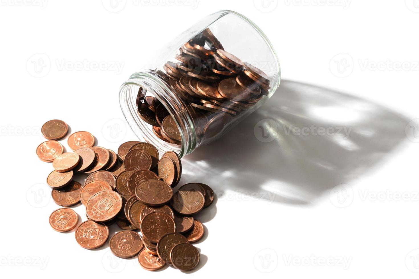 Shiny copper euro coins spilled from a glass jar. photo