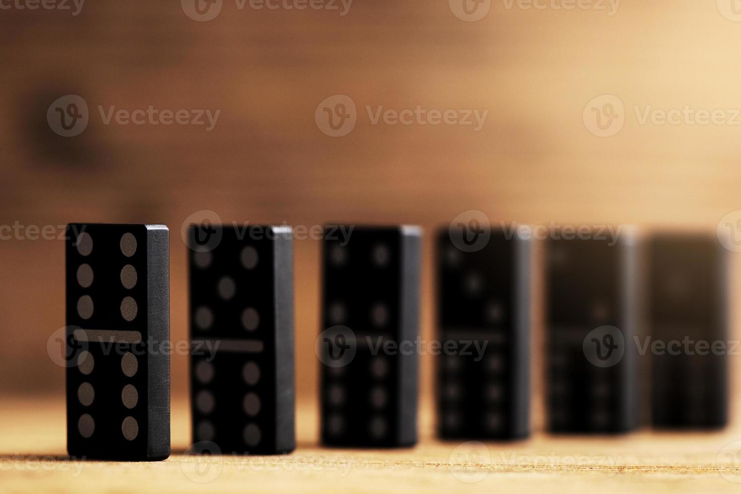 Chain of black plastic domino tiles with white symbols standing one after another. photo