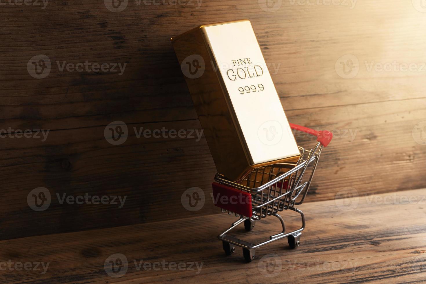 Large shiny gold bar put in a tiny shopping cart. photo