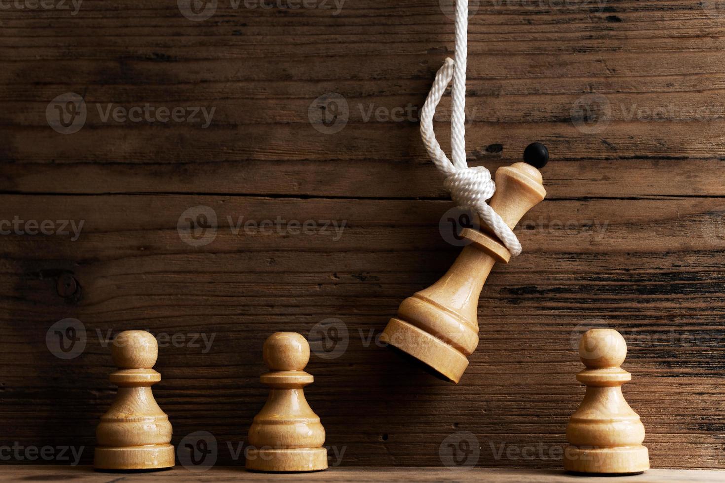 reina de ajedrez de madera colgando de una cuerda blanca con peones debajo. foto