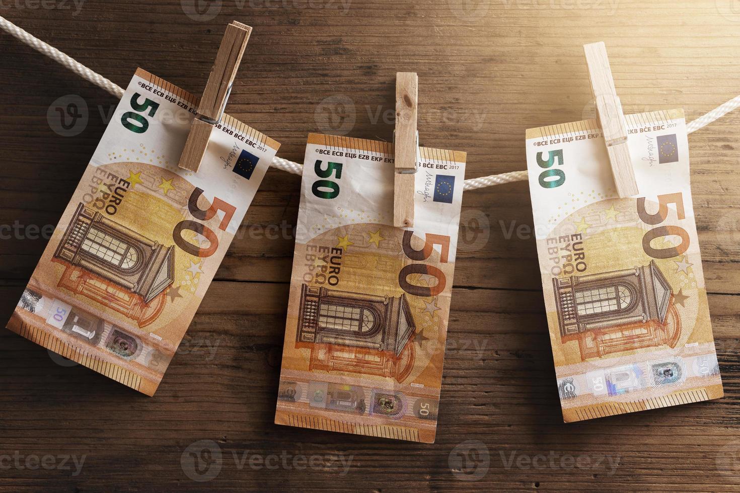 Fifty euro banknotes are drying on a white rope, held by clothespins. photo