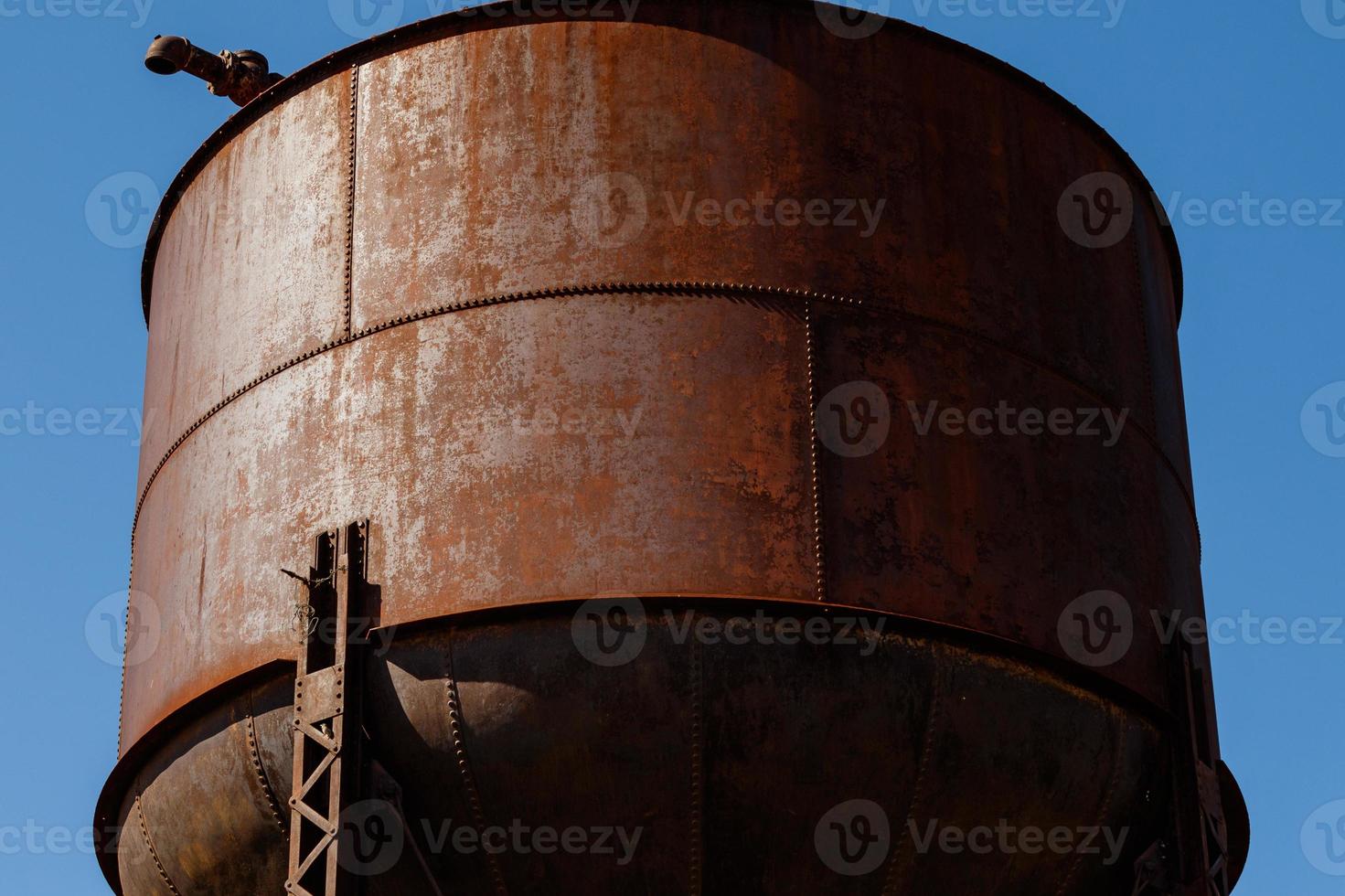 Old rusty water tower on blue sky background photo