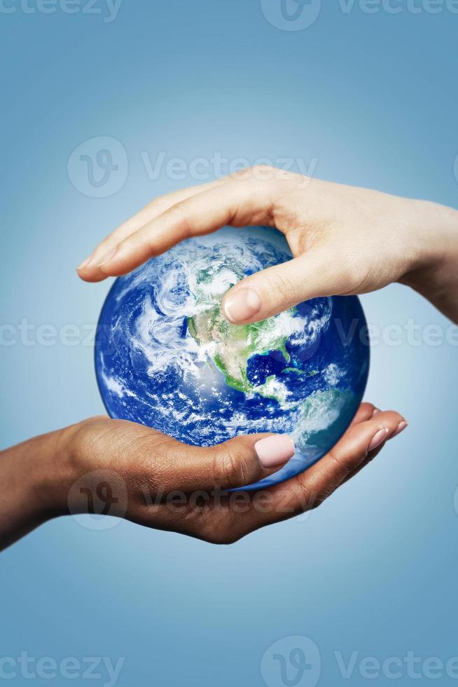 African and Caucasian female hands holding earth globe. Elements of this image furnished by NASA. photo