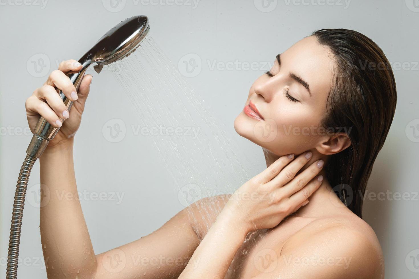 Beautiful sensual woman washing under shower spray photo