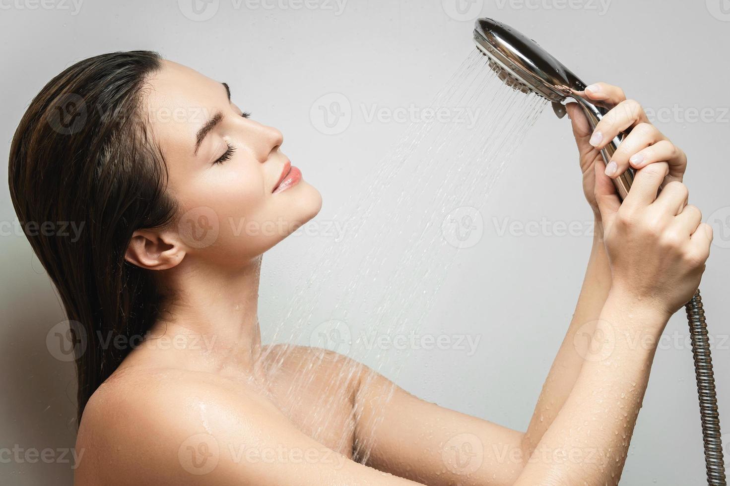 Beautiful sensual woman washing under shower spray photo