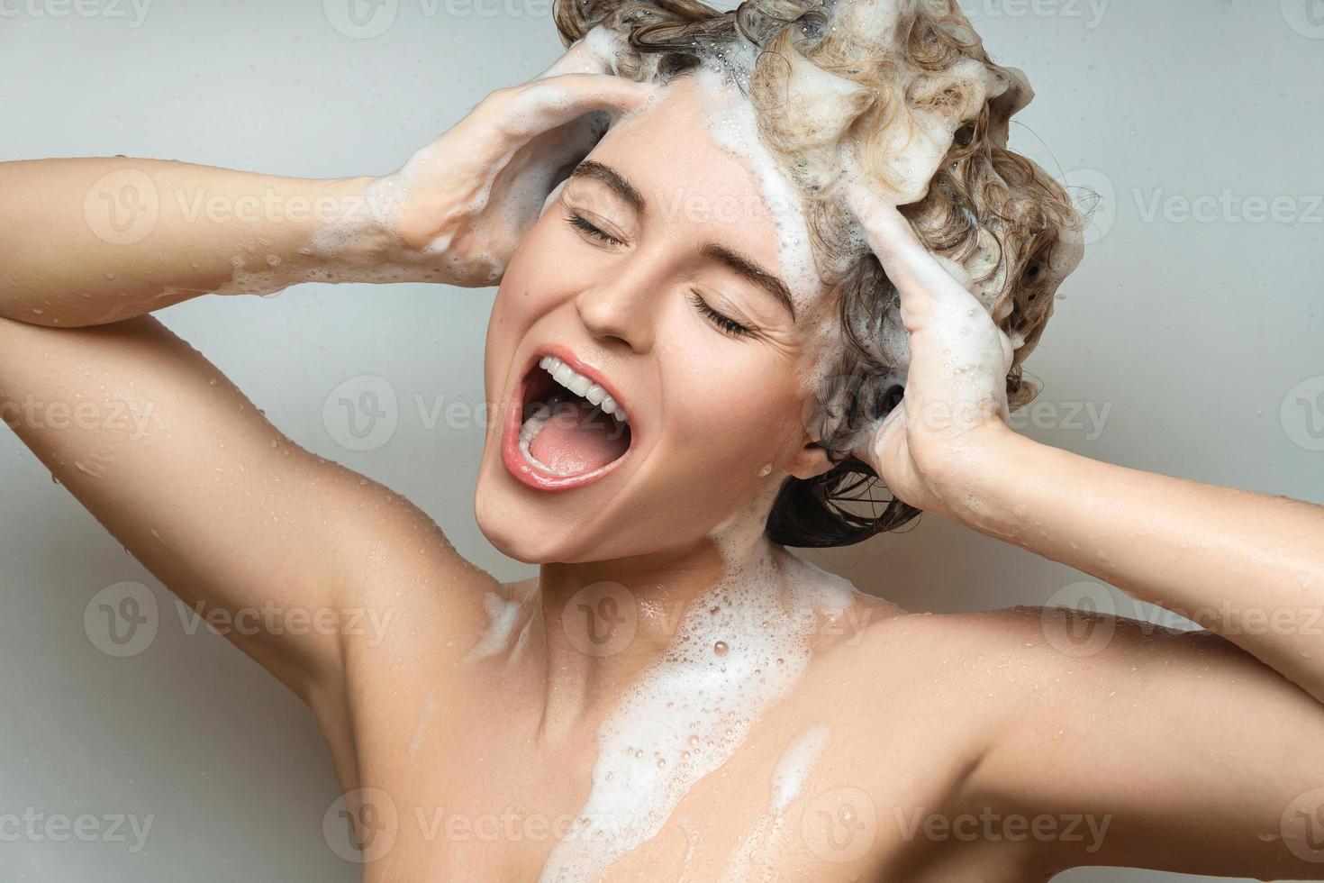 joven hermosa mujer cantando y lavándose el pelo con champú foto