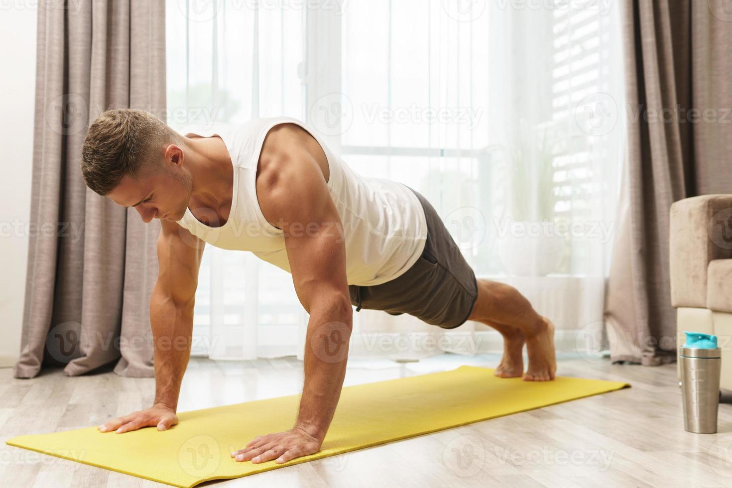 Muscular man doing push-ups during home workout photo