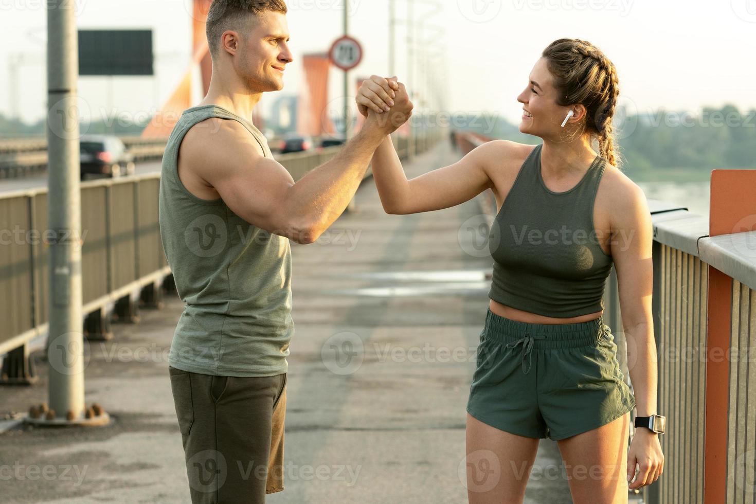 Athletic couple making handshake during fitness workout on city street photo