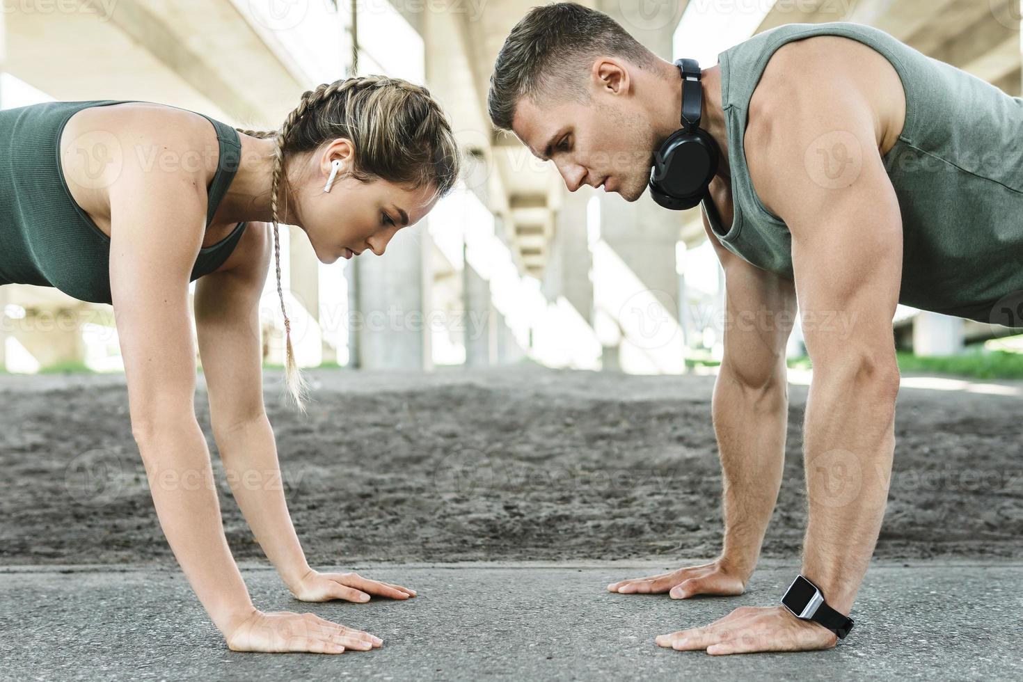 Athletic couple and fitness training outdoors. Man and woman doing push-ups exercise. photo