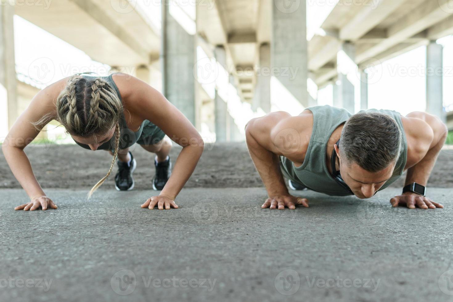 Athletic couple and fitness training outdoors. Man and woman doing push-ups exercise. photo