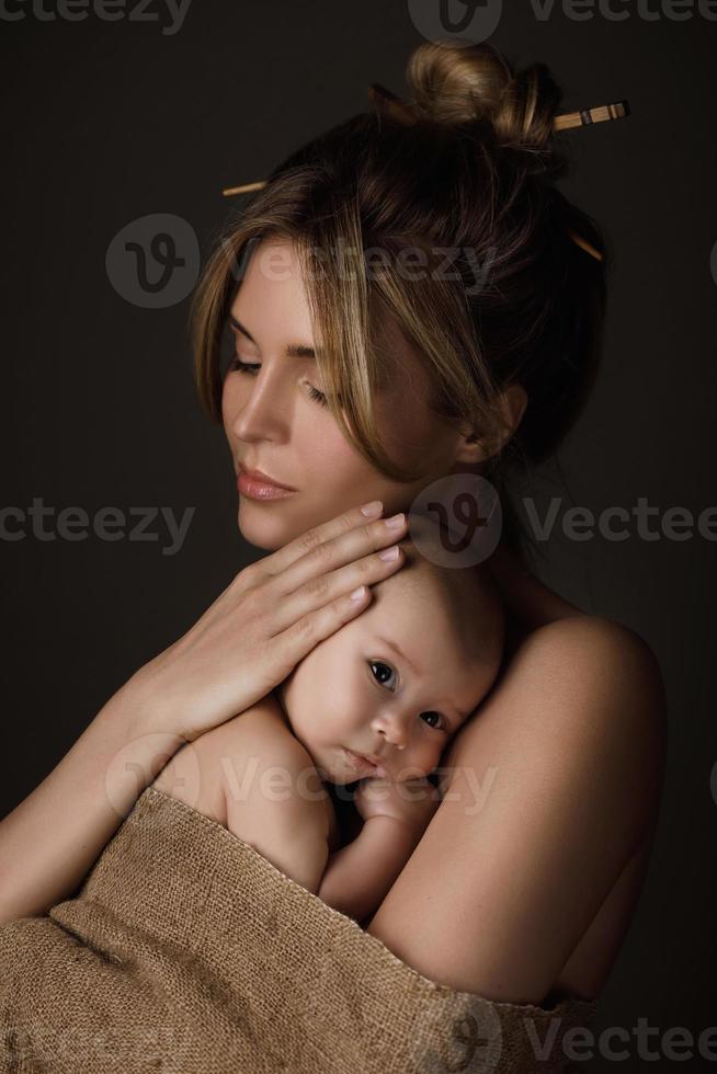 hermosa madre y su pequeño bebé están envueltos en tela de saco foto