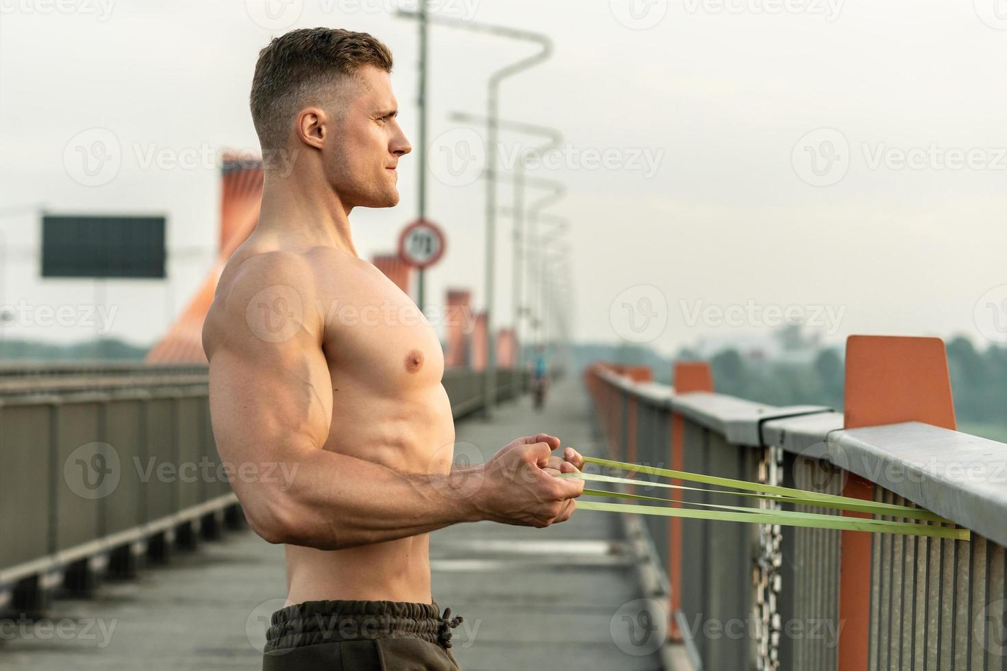 Muscular man during workout with a resistance rubber band on a street photo