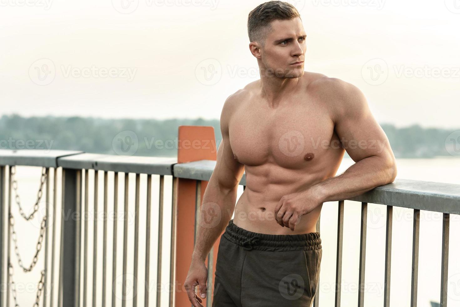 Muscular man with naked torso during fitness workout on a bridge photo