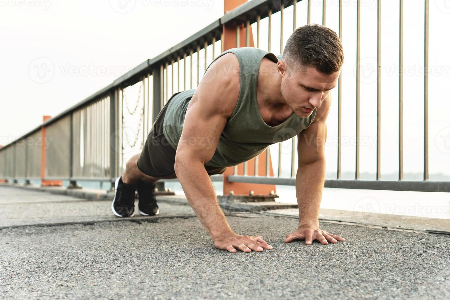 Muscular man is doing push-ups during calisthenic workout on a street photo