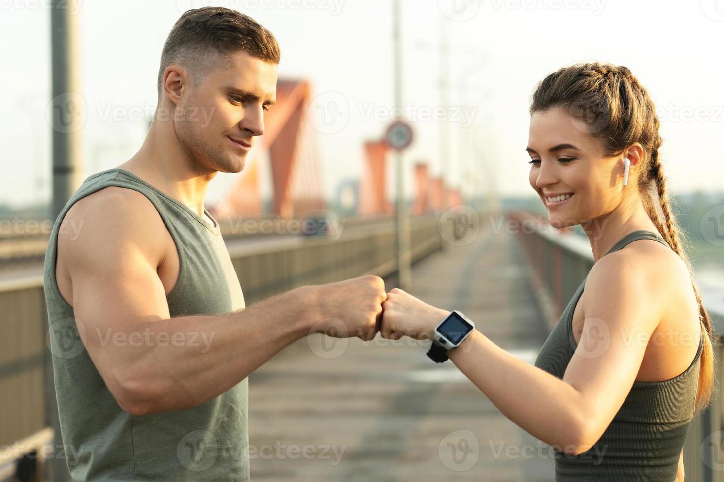 Athletic couple making fist bump gesture during fitness workout on city street photo