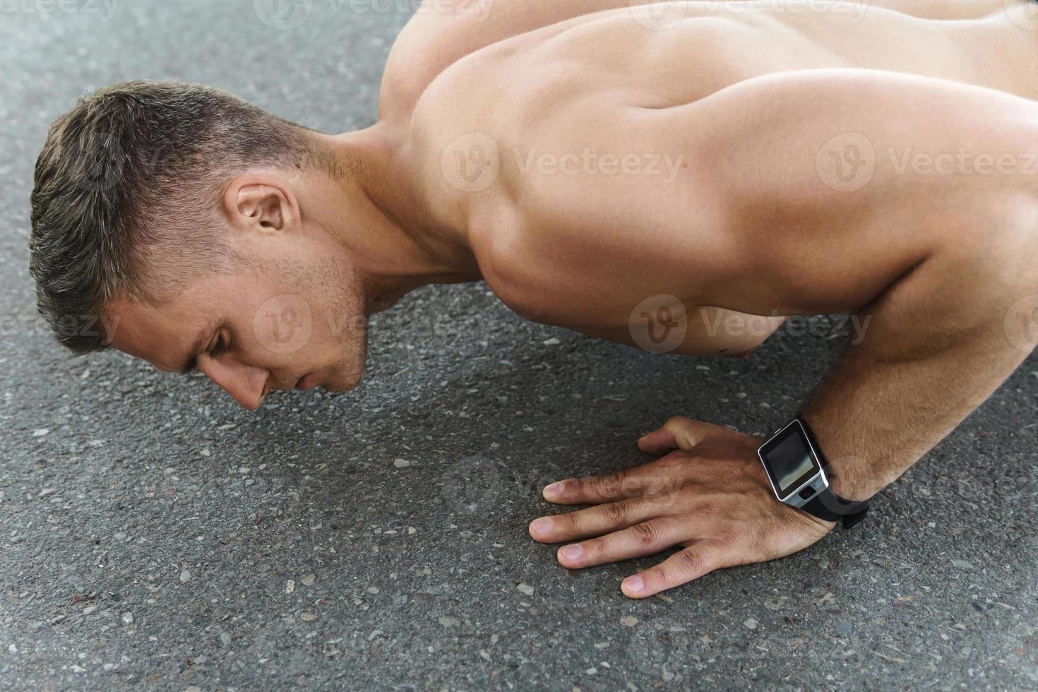 Muscular man is doing push-ups during calisthenic workout on a street photo