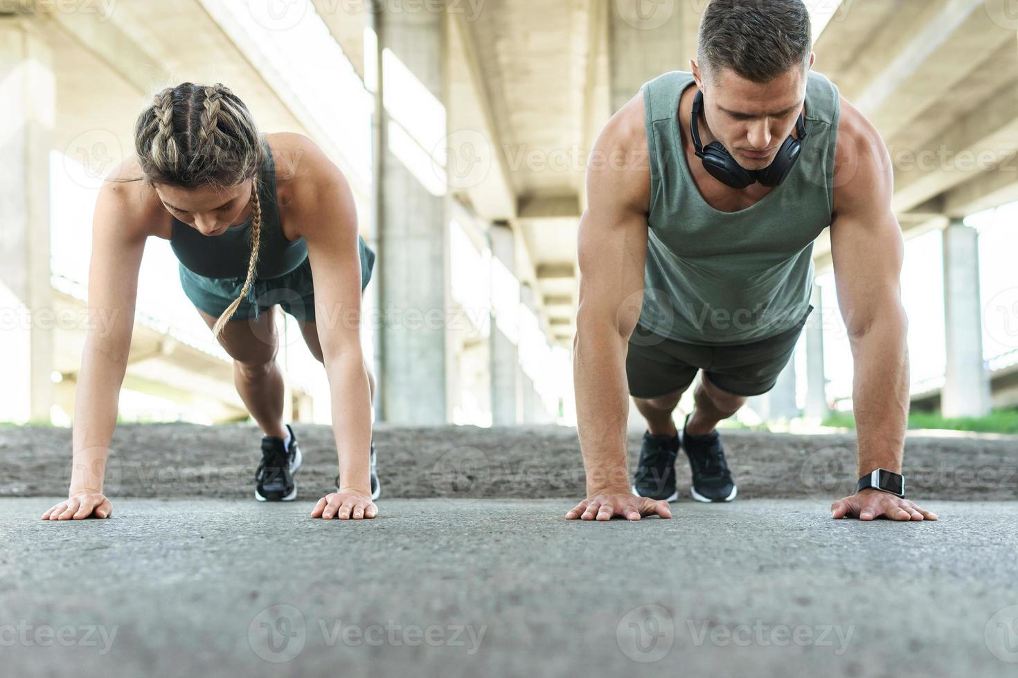 pareja atlética y entrenamiento físico al aire libre. hombre y mujer haciendo ejercicio de flexiones. foto