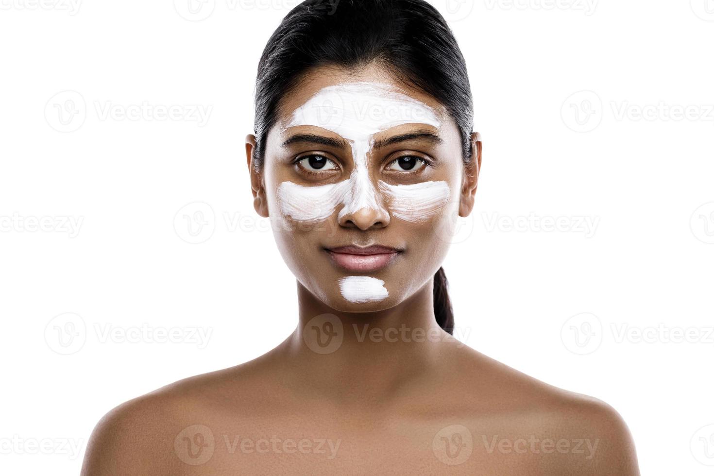 Young indian woman with a cleansing mask applied on her face photo