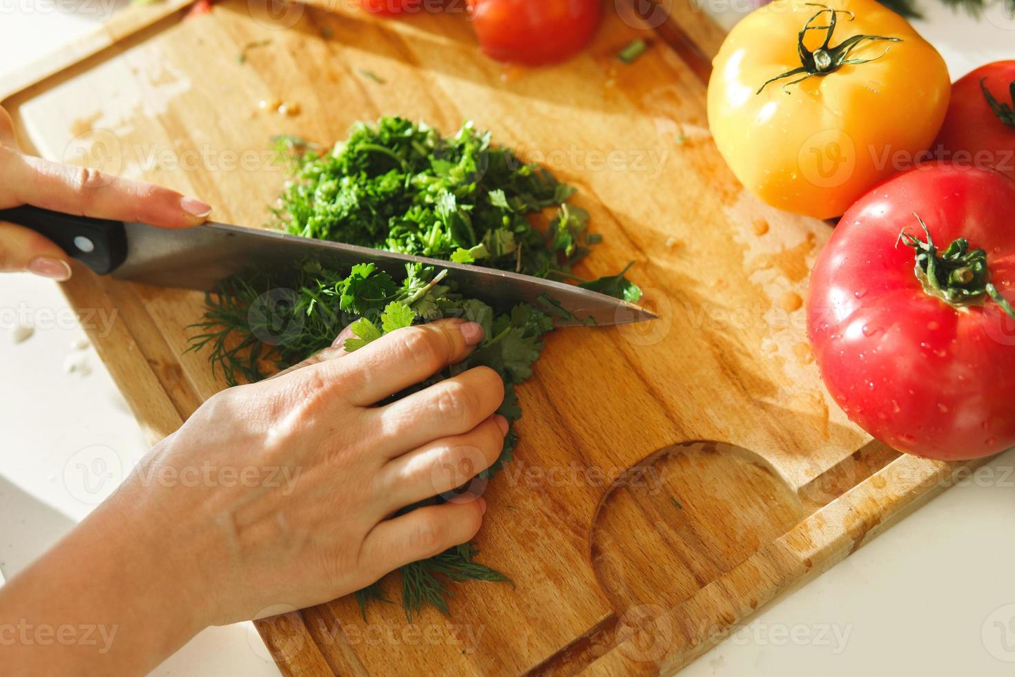 Woman chopping parsley and dill for healthy vegetarian salad photo