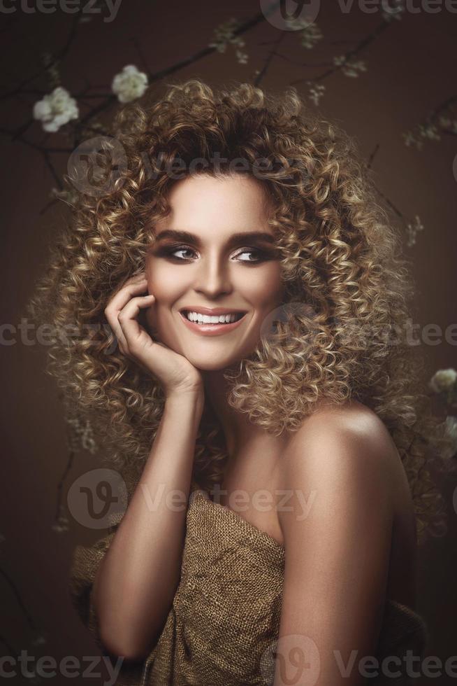 encantadora mujer joven con peinado afro y hermoso maquillaje con muchas flores blancas foto