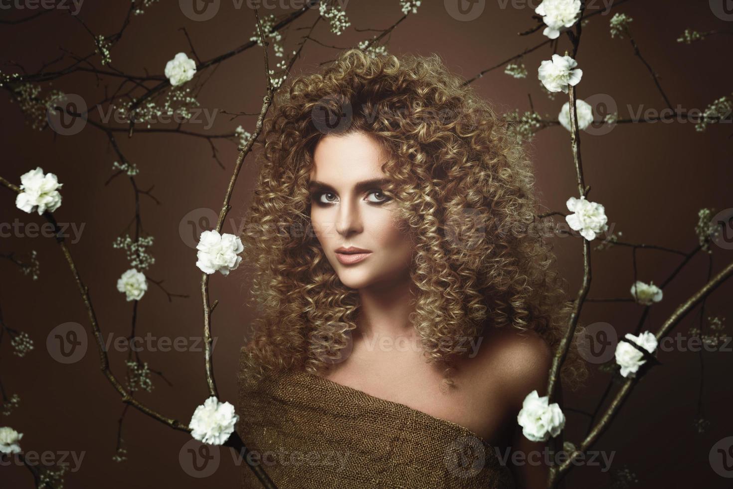 Lovely young woman with Afro hairstyle and beautiful make-up with a lot of white flowers photo