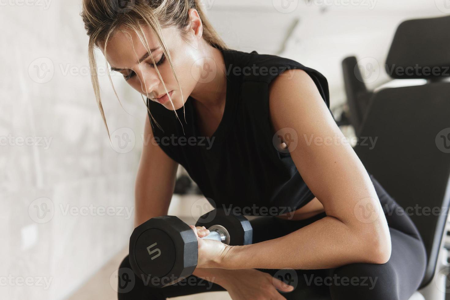 Athletic woman doing bicep curl exercise with a dumbbells in the gym photo