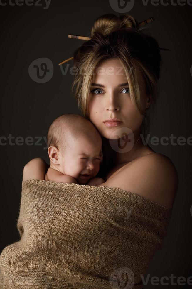 hermosa madre y su pequeño bebé están envueltos en tela de saco foto