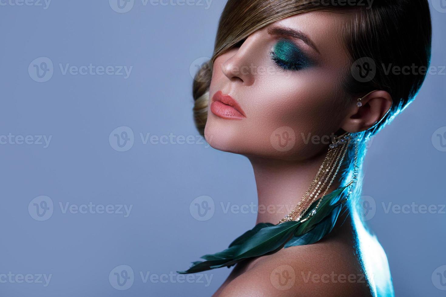 modelo en imagen elegante con cabello liso que cubre un ojo y arete de plumas foto