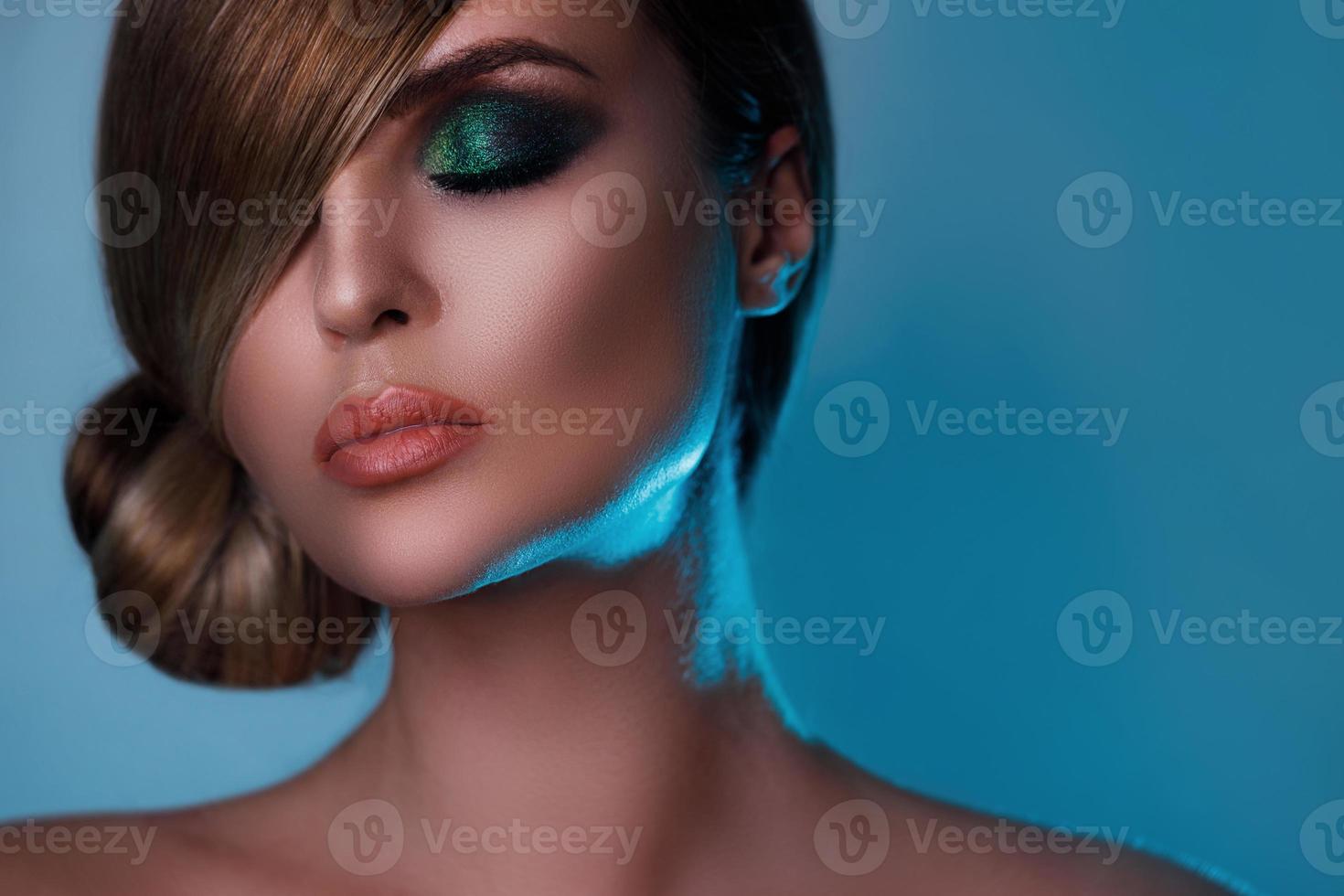 Model in stylish image with sleek hair covering one eye and beautiful green eyeshadows on another photo