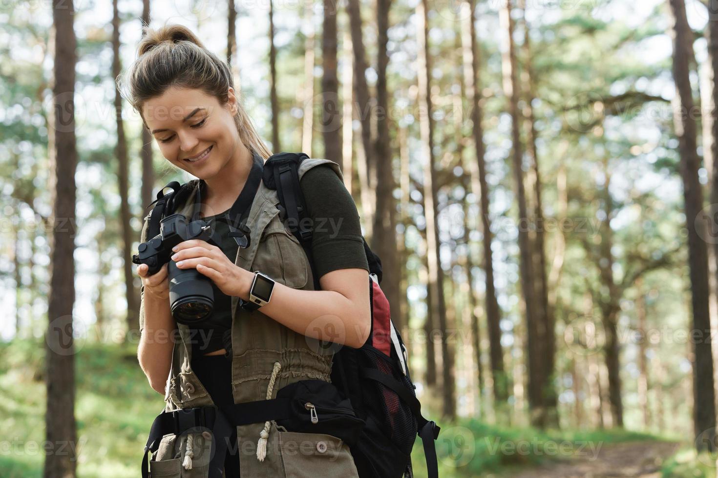 Hiker using modern mirrorless camera in green forest photo