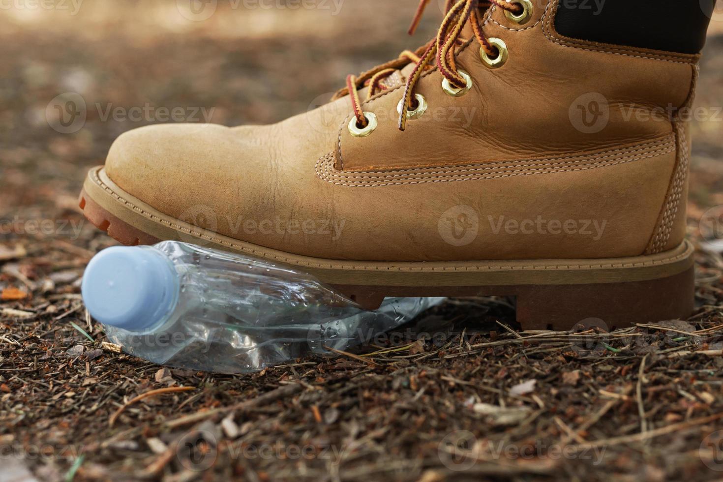 Yellow boots and plastic bottle in a forest photo