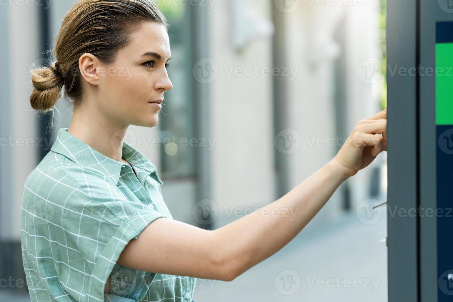 Attractive woman paying in the parking meter machine photo