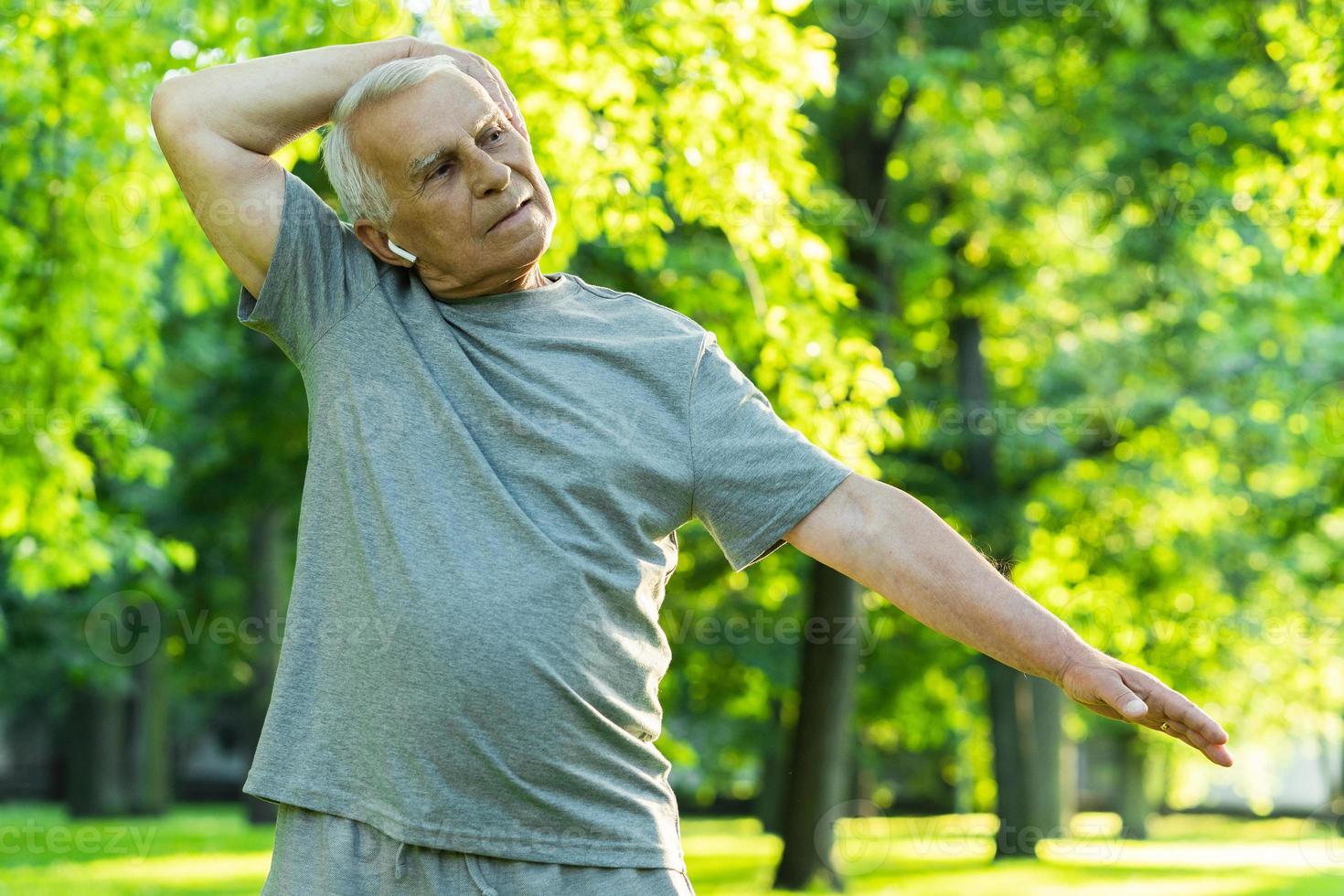 Elderly man exercising in green city park during his fitness workout photo