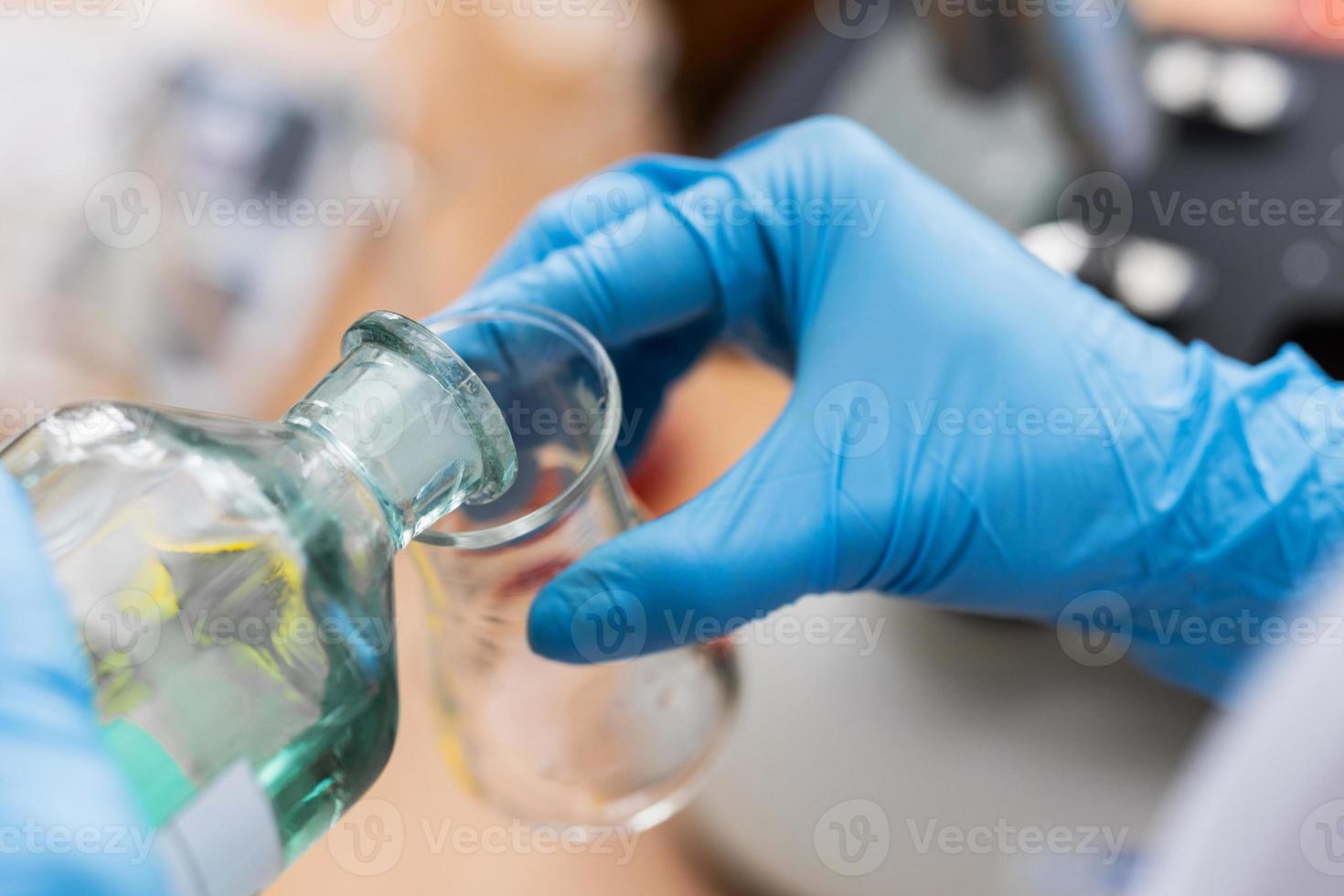 Scientist pouring substance from one flask to another in a laboratory photo