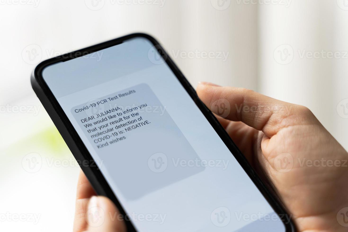 Hands and smartphone with a message showing negative result of PCR test of COVID-19. photo