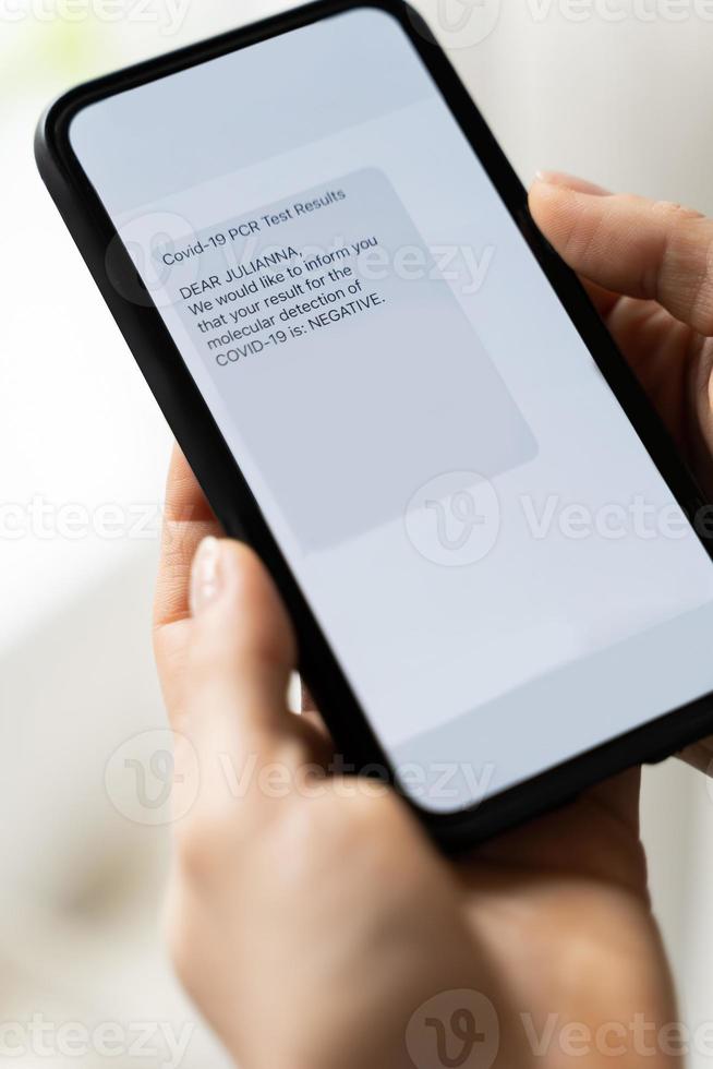 Hands and smartphone with a message showing negative result of PCR test of COVID-19. photo