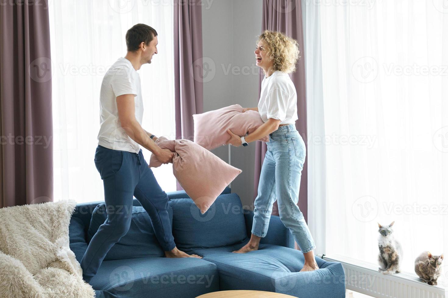 pareja feliz durante la pelea de almohadas en su apartamento foto