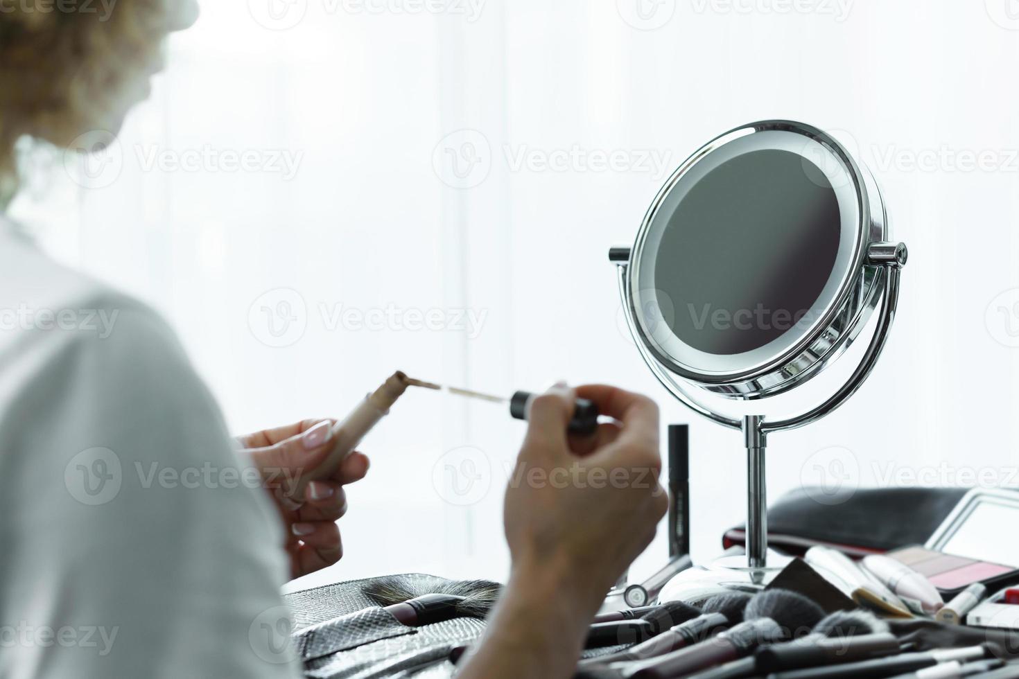 Round mirror for makeup and female hands with a liquid concealer photo