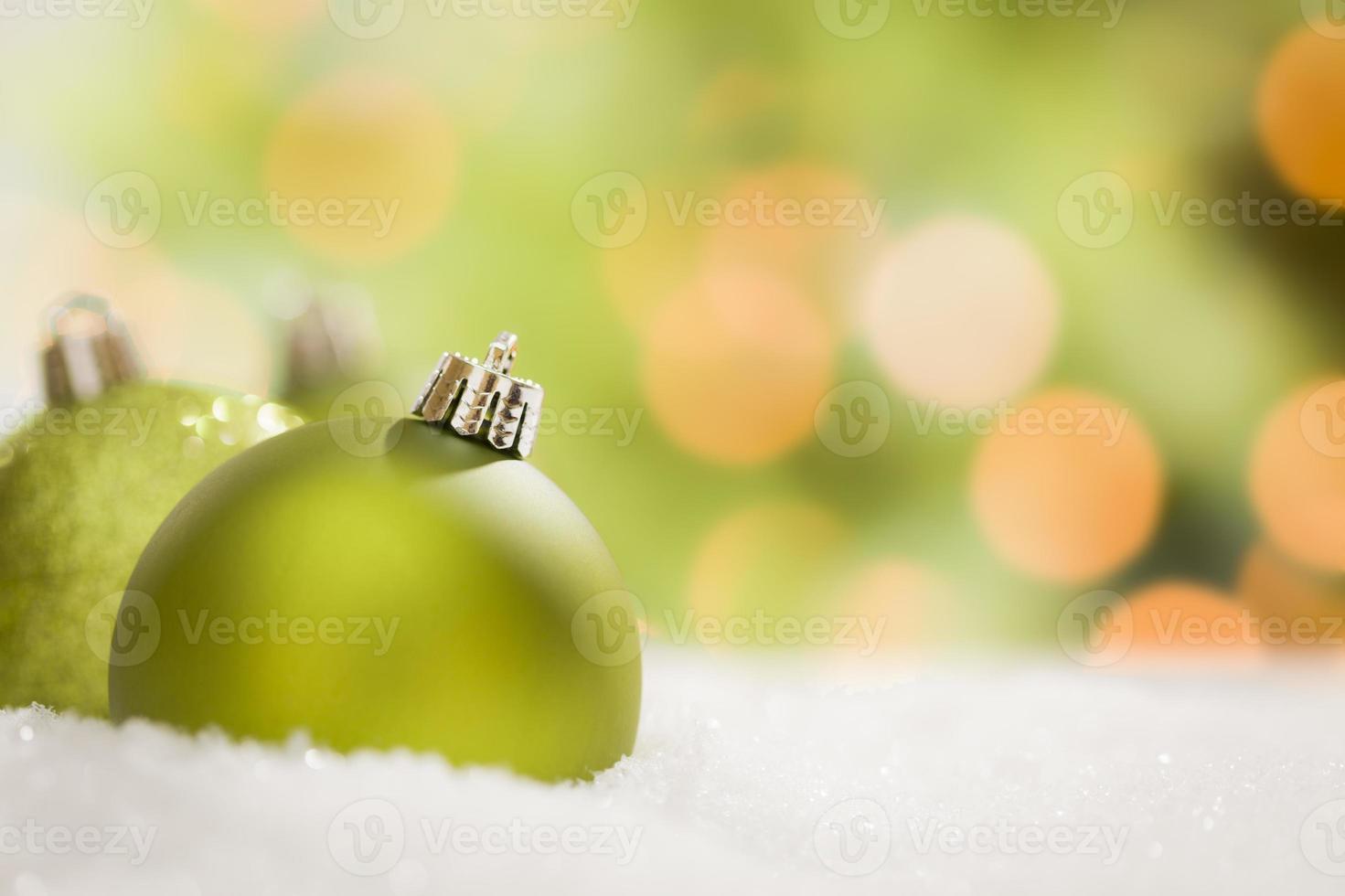 Green Christmas Ornaments on Snow Over an Abstract Background photo