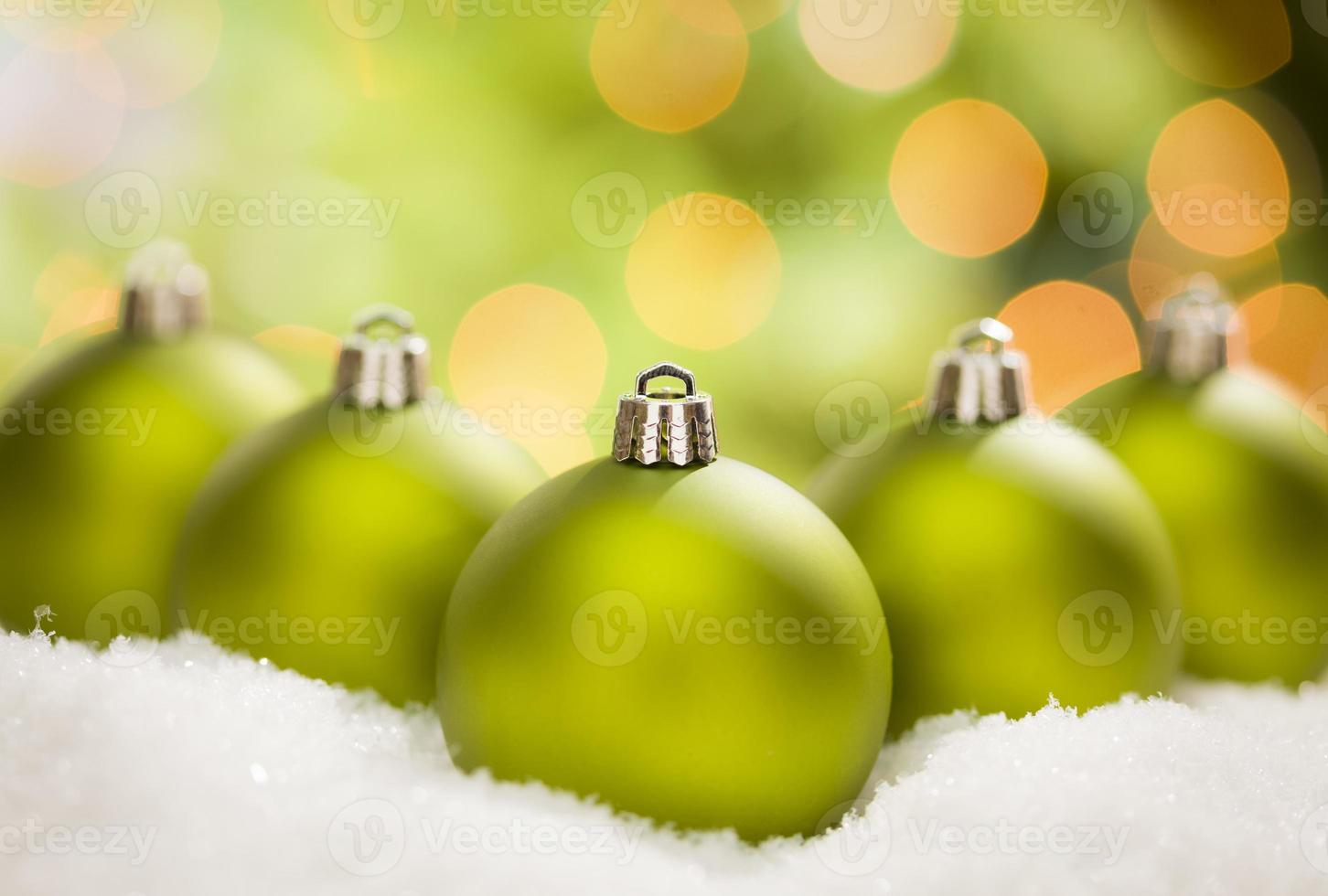 Green Christmas Ornaments on Snow Over an Abstract Background photo