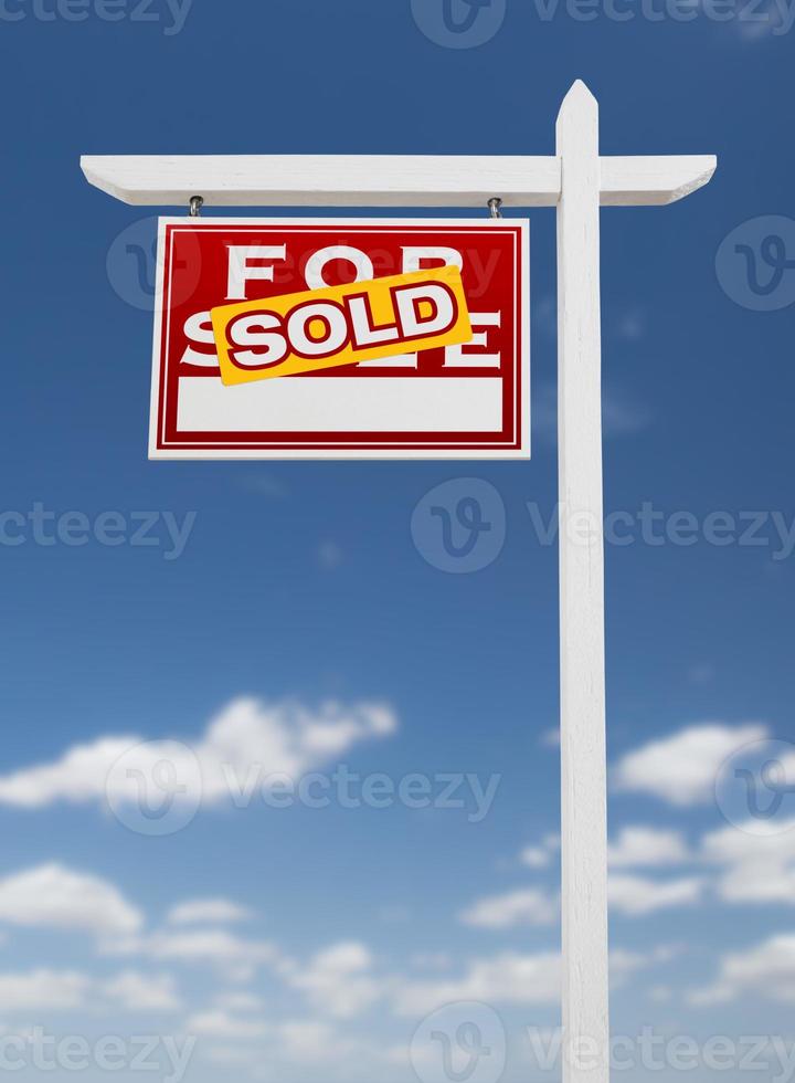 hacia la izquierda se vende en venta signo de bienes raíces en un cielo azul con nubes. foto