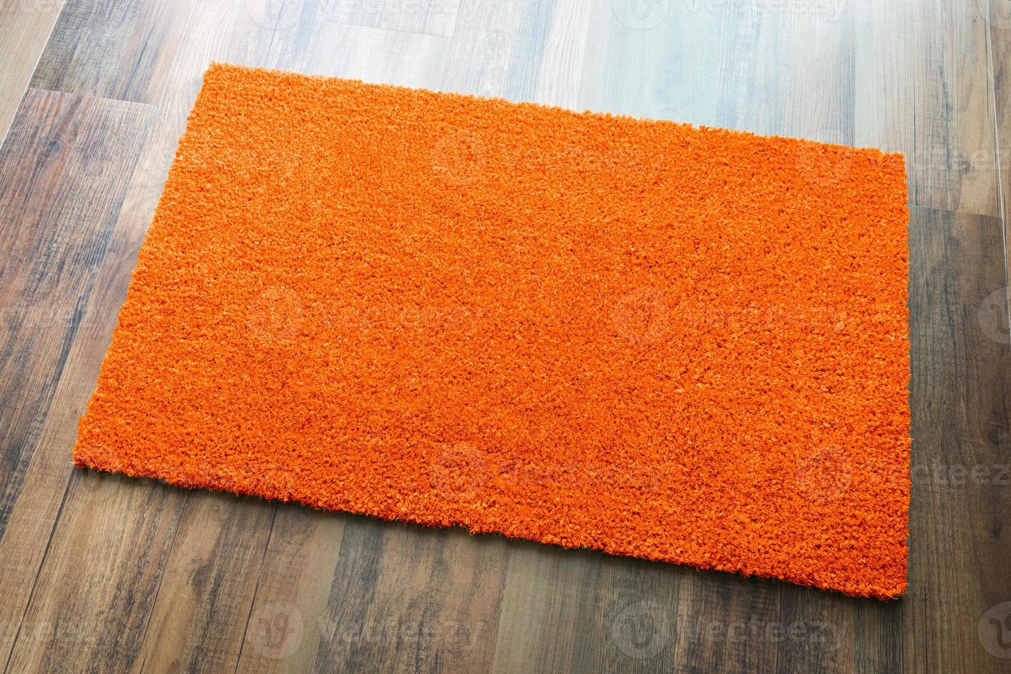 alfombra de bienvenida naranja en blanco sobre fondo de piso de madera lista para su propio texto foto