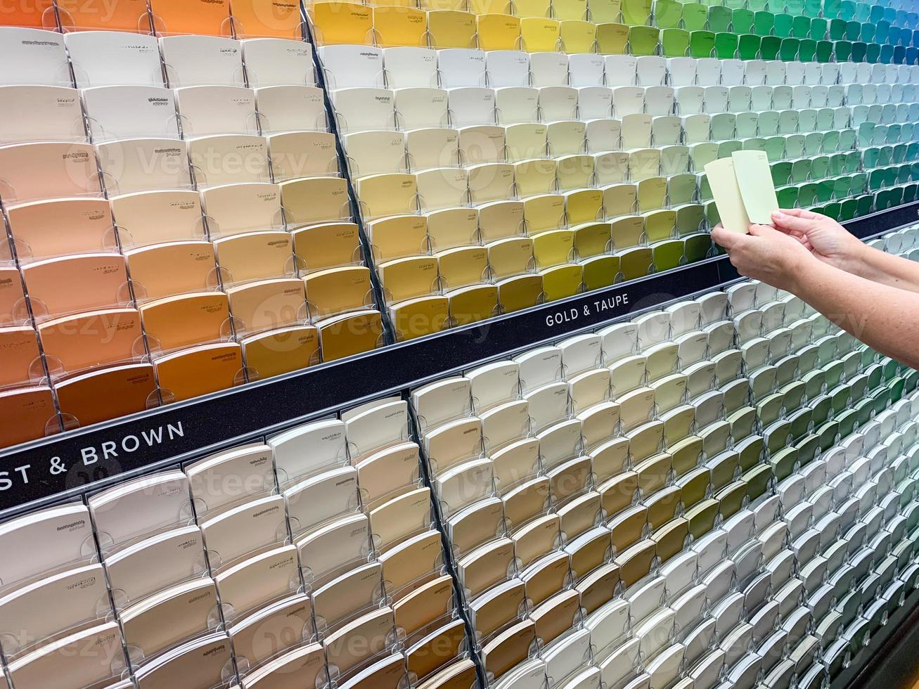 el cliente ve muestras de pintura en la tienda de pintura en un colorido estante de muestras foto