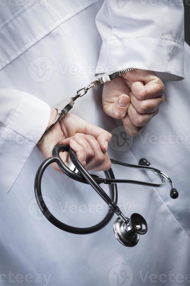 Female Doctor or Nurse In Handcuffs Holding Stethoscope photo