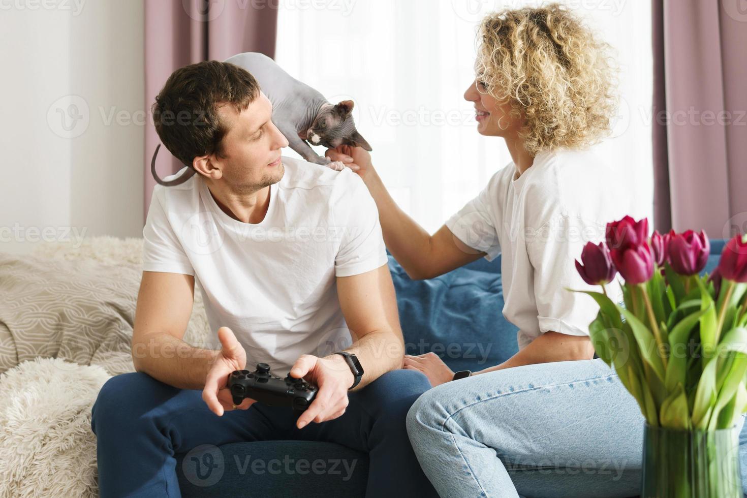 Couple and their Sphynx cat are relaxing at home photo