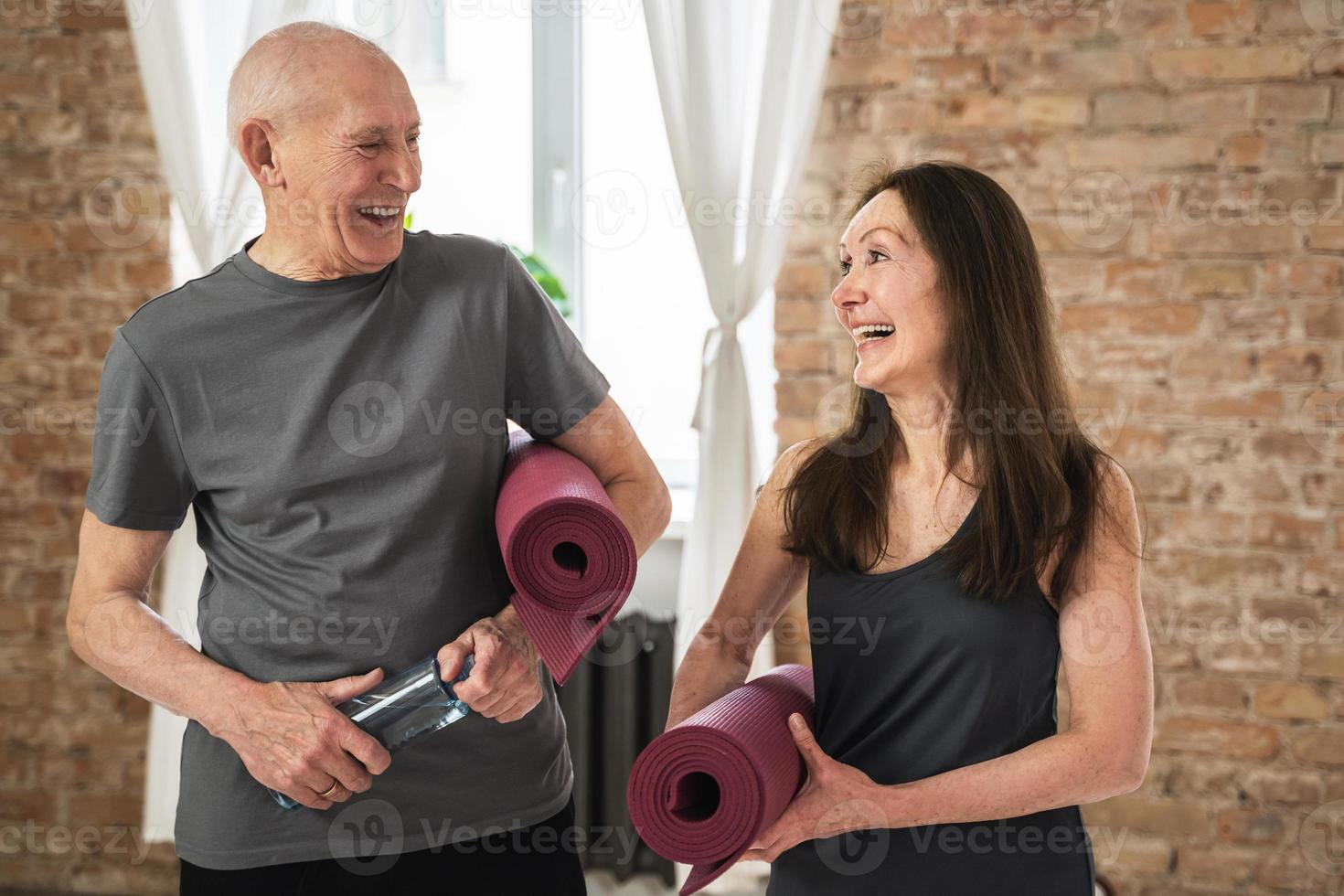 Two cheerful and active old people with exercising mats ready for workout photo